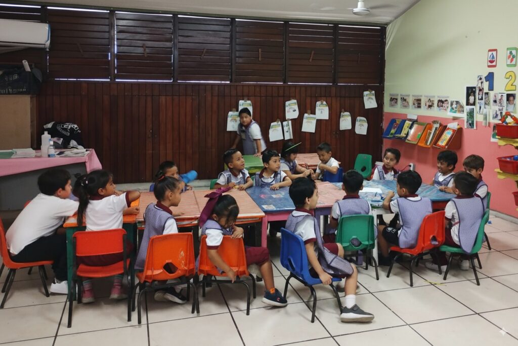 Grupo de alumnos sentados en mesa de trabajo escuela